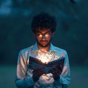 Photographie d'un homme lisant un livre lumineux dans la pénombre